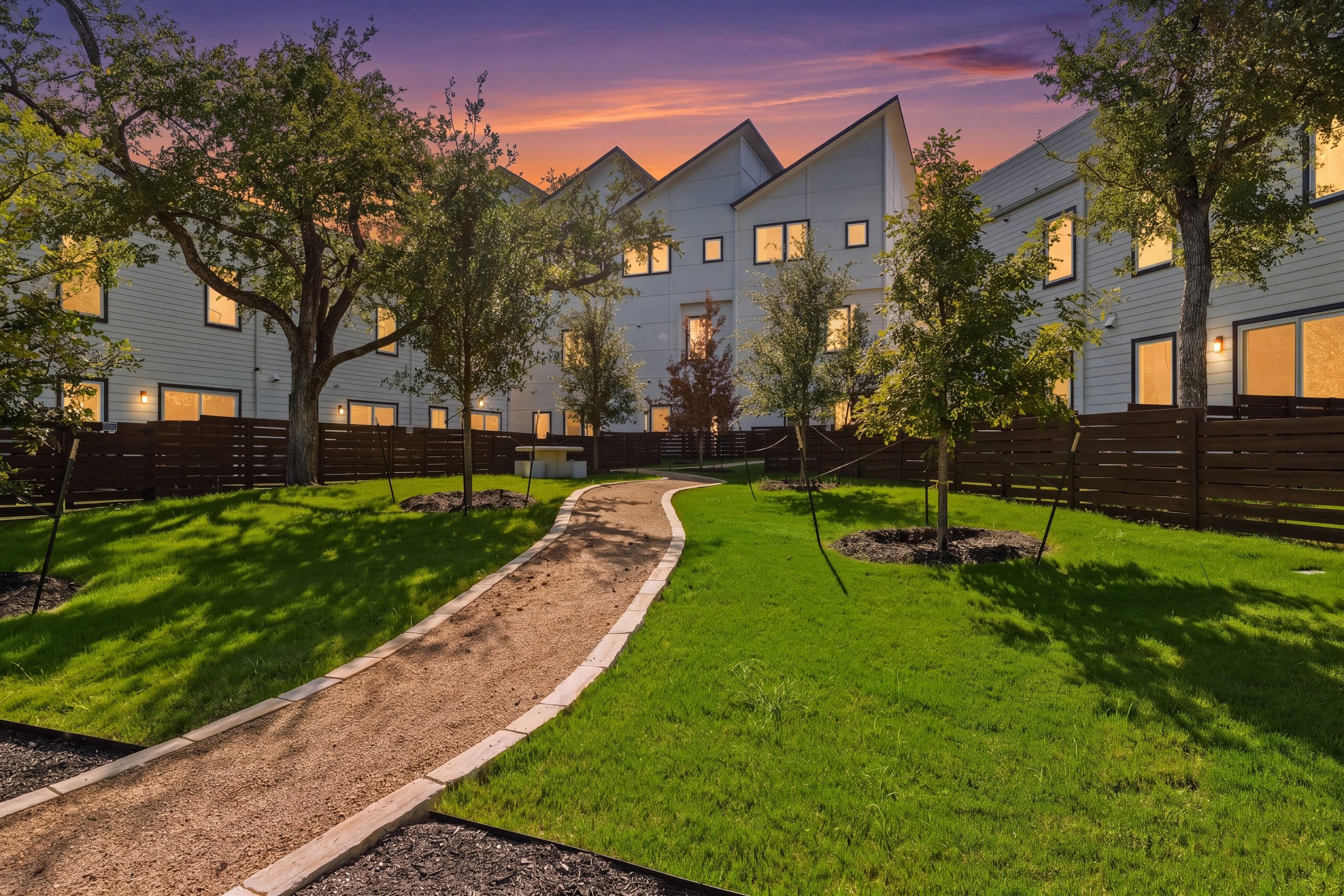 Overlook community green space and walking path at twilight with the townhomes lit beyond